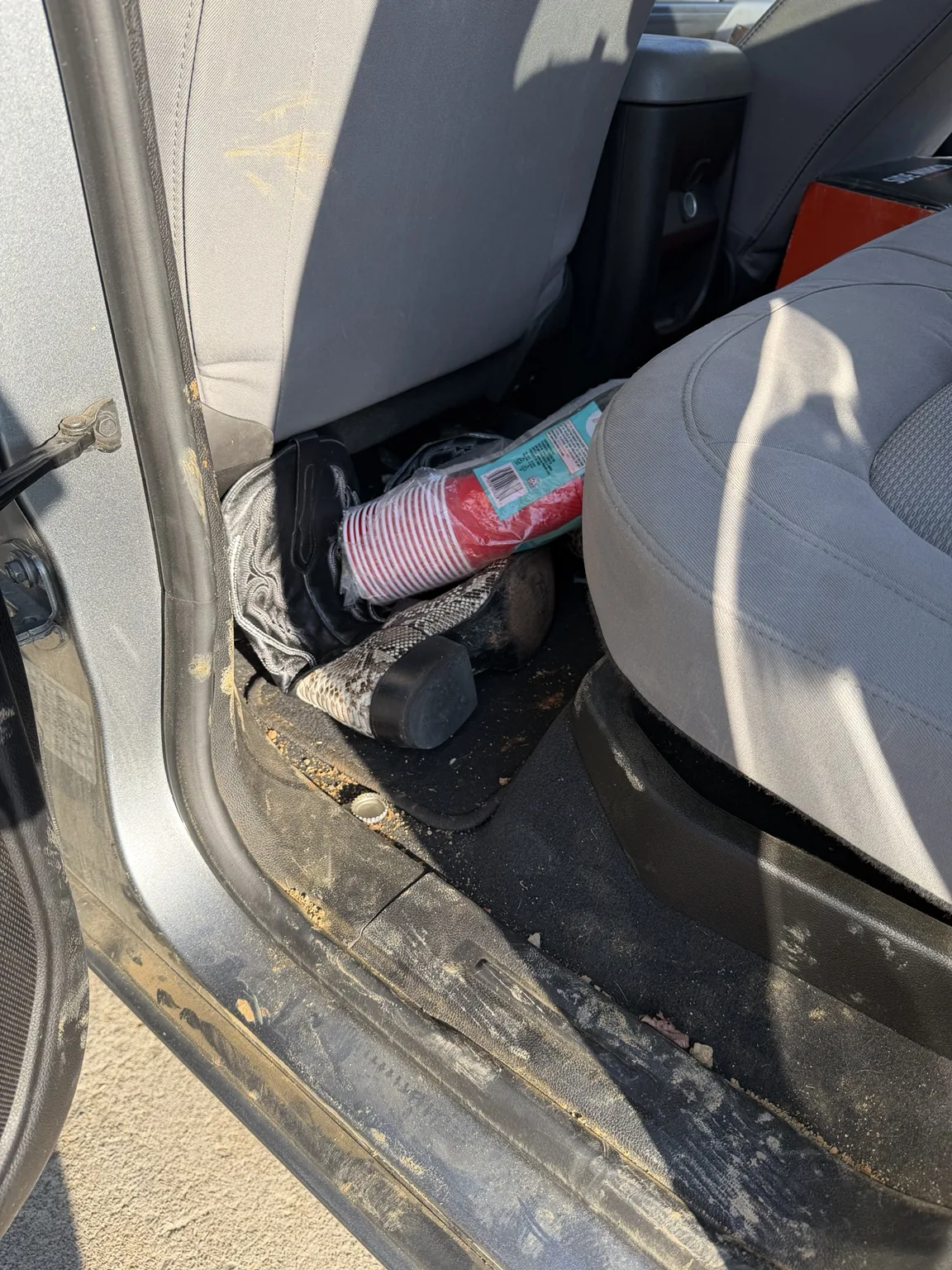 Vehicle interior before detailing with debris and dirt in the footwell